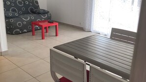 Une pièce comprenant un lit, une petite table, un canapé et une fenêtre avec des rideaux.