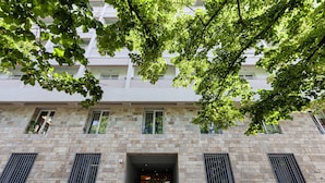 Um edifício de vários andares com fachada de pedra, janelas amplas e uma entrada central.