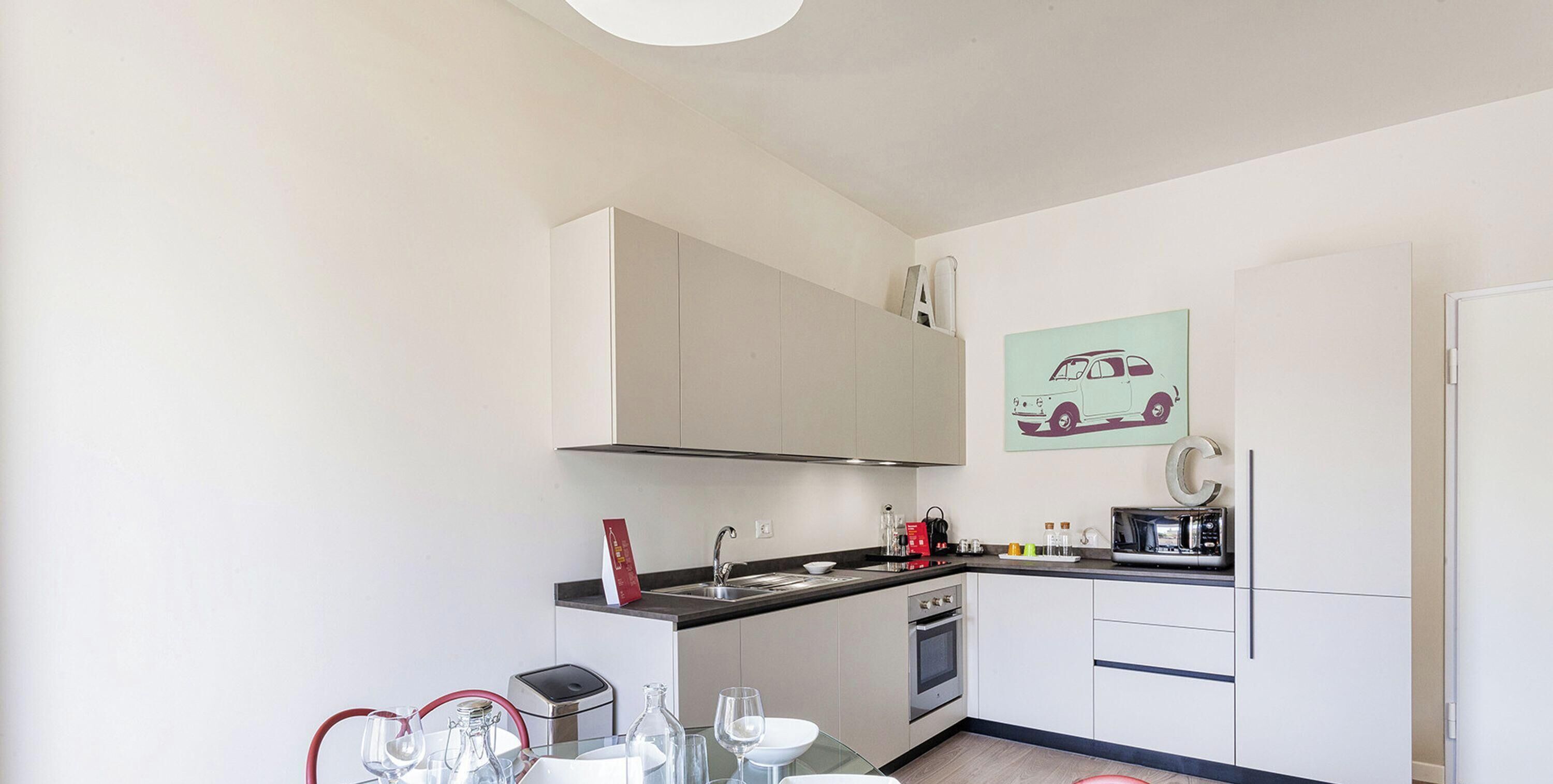 Una cucina compatta con forno a microonde, tostapane e lavello.