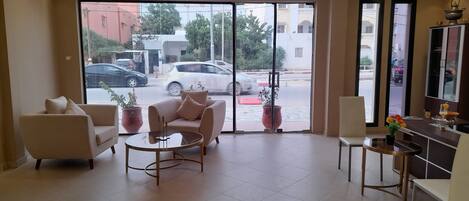 A hotel lobby with a sofa, chairs, a coffee table, and a dining area.