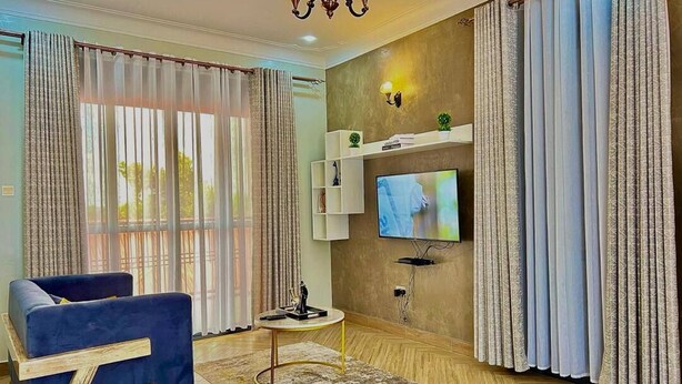 A modern living room with a sofa, TV, and decorative items. - Eden Homes (Kampala)