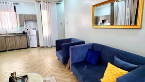 A modern living room with a blue sofa, a coffee table, and a chandelier. - Eden Homes (Kampala)