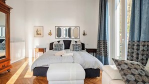 A bedroom with a large bed, a dresser, a nightstand, a mirror, and a window with curtains. - Former palace, picturesque apartment, lake view (Lombardia)
