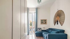 A modern living room with a blue sofa, a patterned floor, a wall-mounted fan, and a painting. - Former palace, picturesque apartment, lake view (Lombardia)