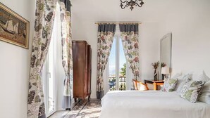 A bedroom with a bed, a desk, a chair, and a view of the outside. - Former palace, picturesque apartment, lake view (Lombardia)