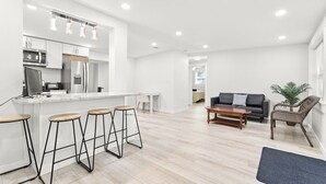 Une cuisine moderne dotée d’un îlot central, de tabourets de bar et d’un coin repas comprenant un canapé et une table basse.