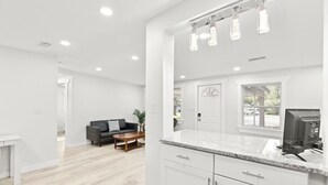 Une cuisine moderne avec des meubles blancs, un plan de travail en granit et un four à micro-ondes encastré.