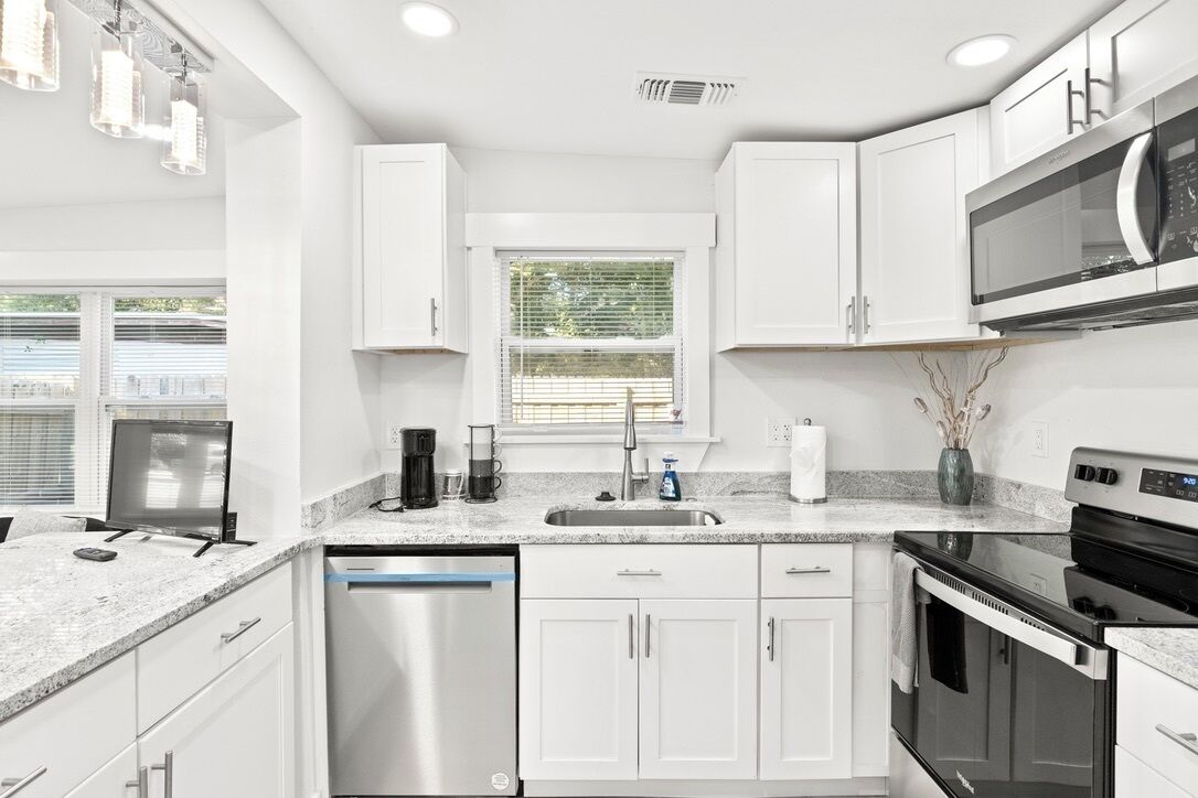 A modern kitchen with white cabinets, stainless steel appliances, and a granite countertop.