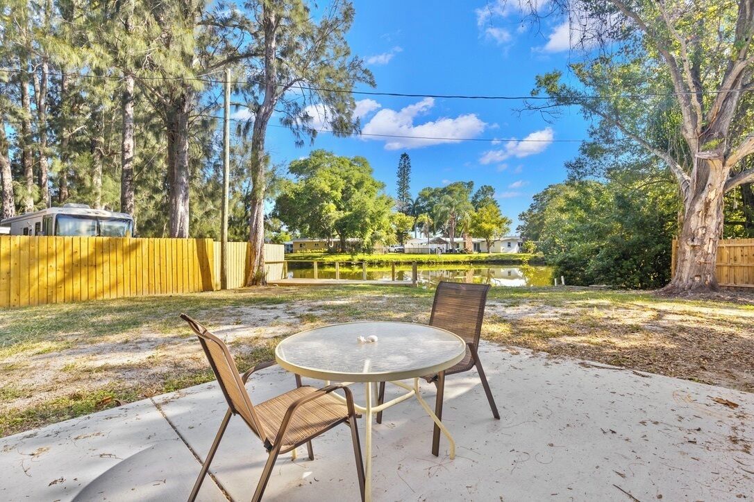 A backyard with a round table and chairs, surrounded by trees and a fence.