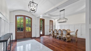 A spacious dining area with a wooden floor, white walls, and a large window. - Buckhead Modern Luxury Home with Firepit & Arcade (Atlanta)