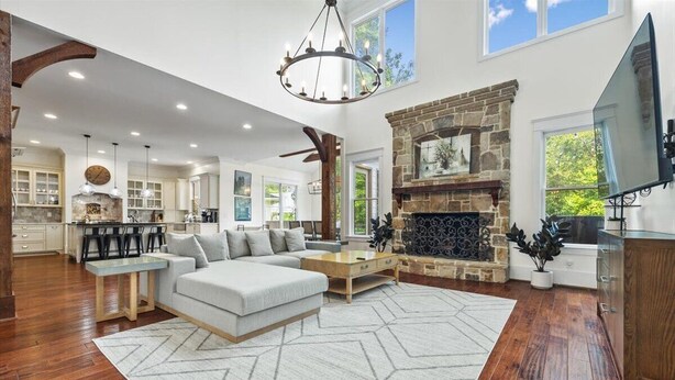 A spacious living room with a fireplace, a large sofa, and a dining area with high ceilings and natural light. - Buckhead Modern Luxury Home with Firepit & Arcade (Atlanta)