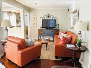 A living room with two leather sofas, a television, and a small table with a plant.