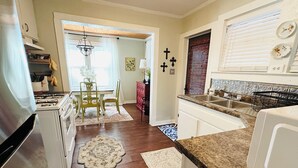 A kitchen with a gas stove, white cabinets, a dining area with a table and chairs, and a patterned rug.