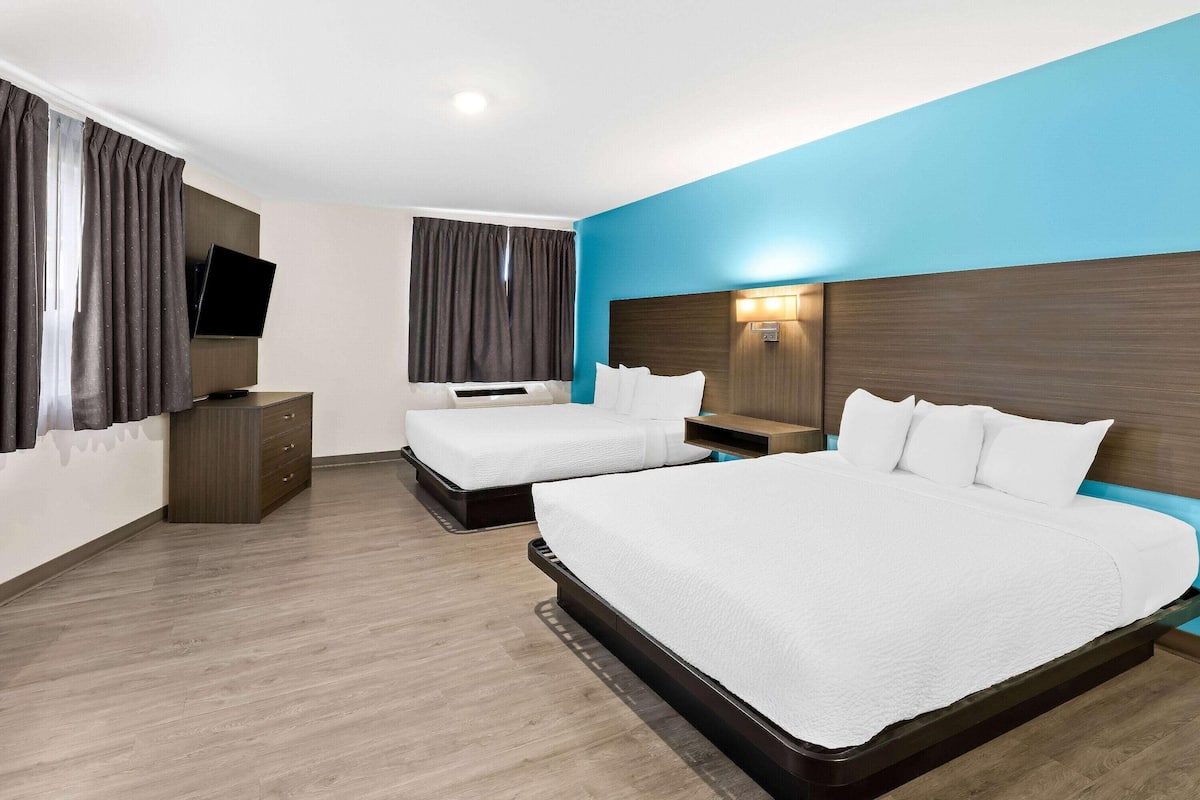 Una habitación de hotel con dos camas, un televisor, un escritorio y una mesita de noche.