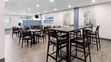 A conference room with a large table and chairs, artwork on the walls, and a modern ceiling.