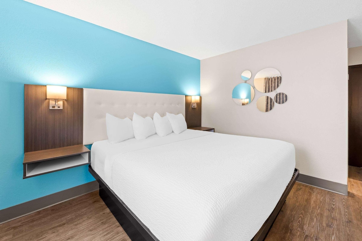 Una habitación de hotel moderna con una cama grande, mesitas de noche empotradas e iluminación en la pared.
