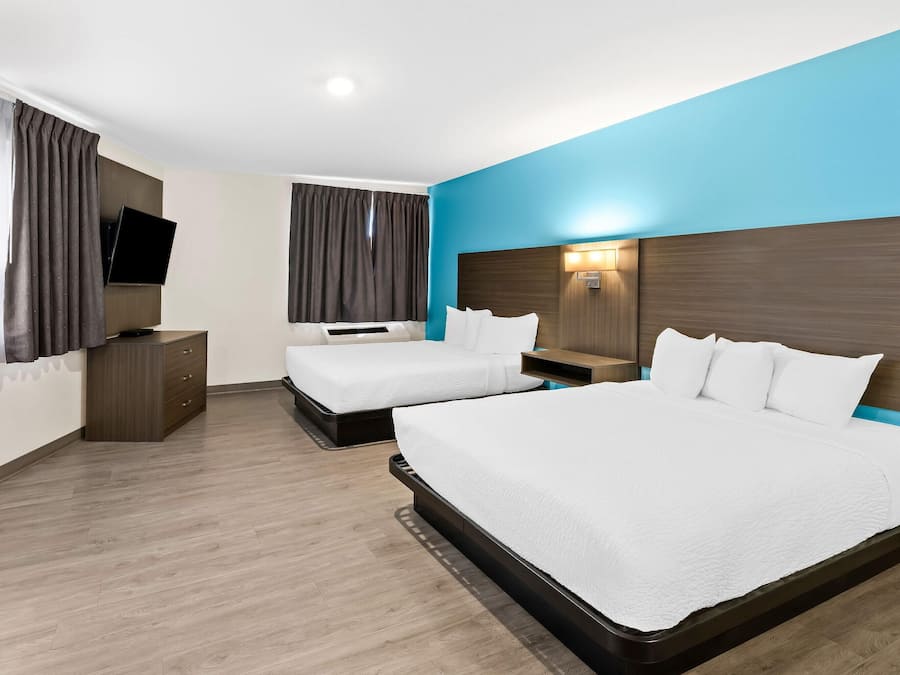 A hotel room with two beds, a flat-screen TV, a wooden dresser, and a nightstand.