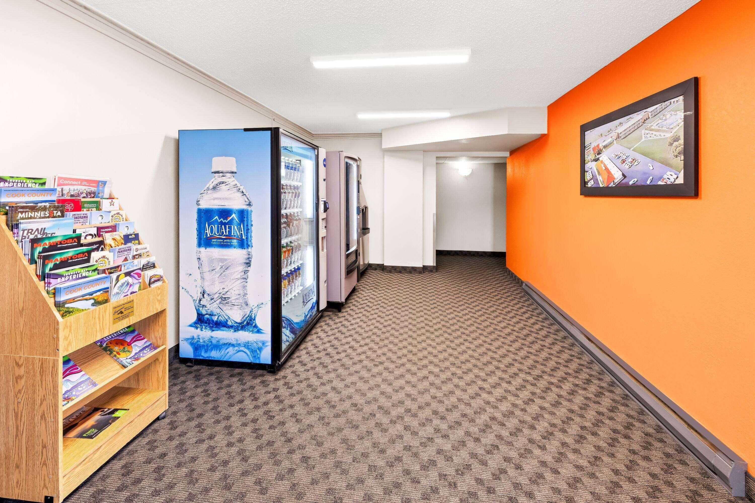 A hallway with a vending machine, a wooden bookshelf, and a framed picture on the wall.