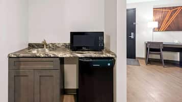 A compact kitchenette with a microwave, sink, and dishwasher.