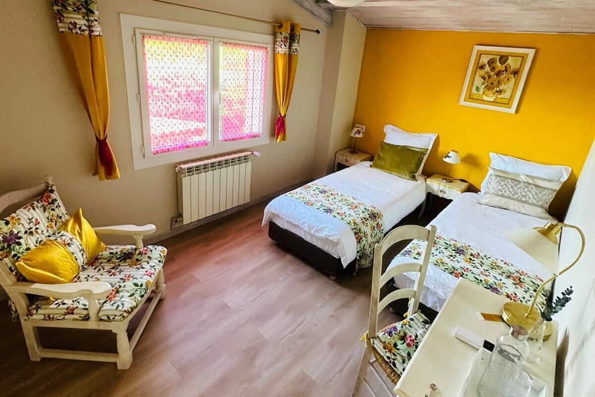 Een gezellige kamer met een bed, een stoel, een bureau en een raam met gordijnen.