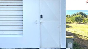 A white building with a garage door, a closed door, and a view of the ocean. - Penthouse Luxe • Vue Mer Panoramique 180° • Terrasse • Plage à pied (Sainte-Anne)