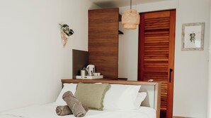 Una camera da letto con un letto, un armadio in legno, un comodino e una lampada a sospensione.