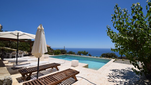 A pool area with lounge chairs and umbrellas, overlooking a clear blue sky and the sea. - Villa Roccella Ionica with Sea View (Roccella Jonica)