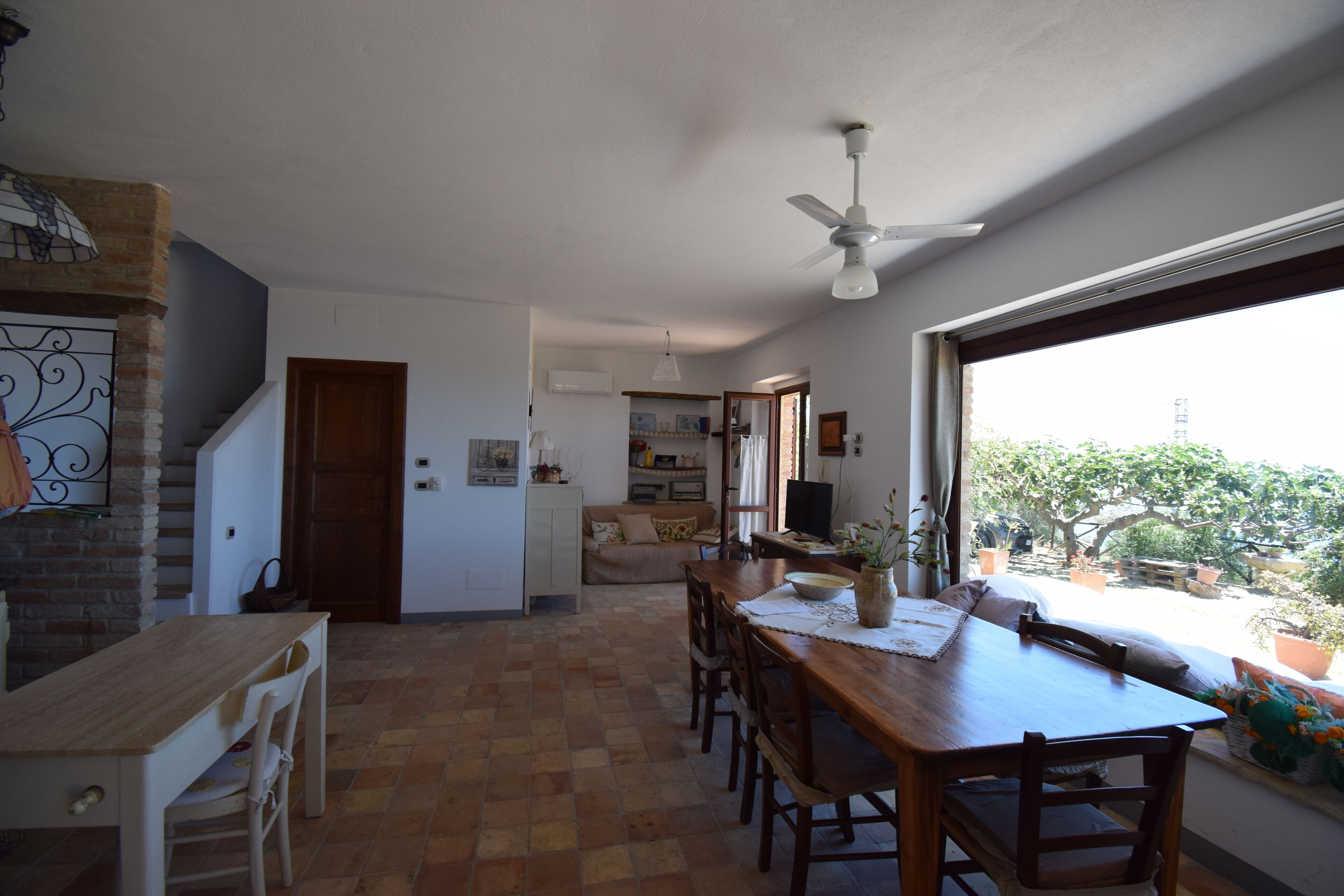 Une cuisine spacieuse avec un coin repas, un escalier et une vue sur l’extérieur.