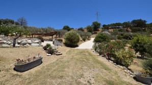A landscaped garden with a pathway, a pergola, and various shrubs and trees. - Villa Roccella Ionica with Sea View (Roccella Jonica)