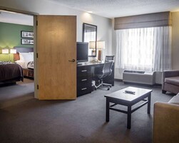 Una habitación de hotel con cama, escritorio, silla y mesita de centro.