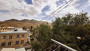 A building with a flat roof and multiple windows, surrounded by trees and mountains in the background. - DADOW Apartments (Naryn)