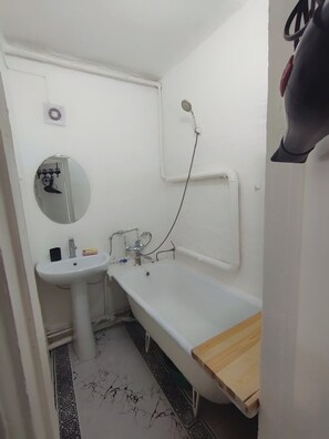 A small bathroom with a sink, mirror, and bathtub. - DADOW Apartments (Naryn)