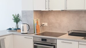 Een moderne keuken met witte kasten, een inbouwoven en een aanrecht met waterkoker en broodrooster.