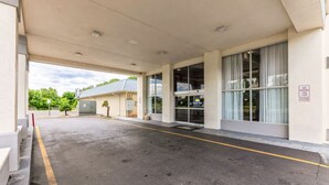 A covered parking area with a building entrance, a no parking sign, and a clear sky. - Days Inn I81 king bed (Roanoke)