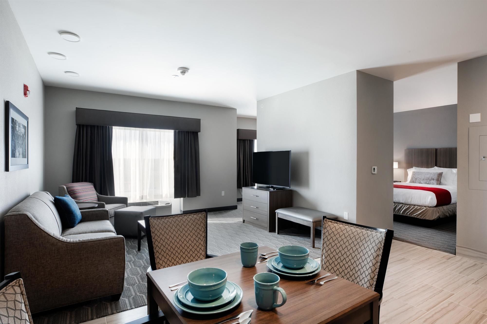 Une chambre d’hôtel comprenant un coin repas, un canapé, une télévision et un lit.