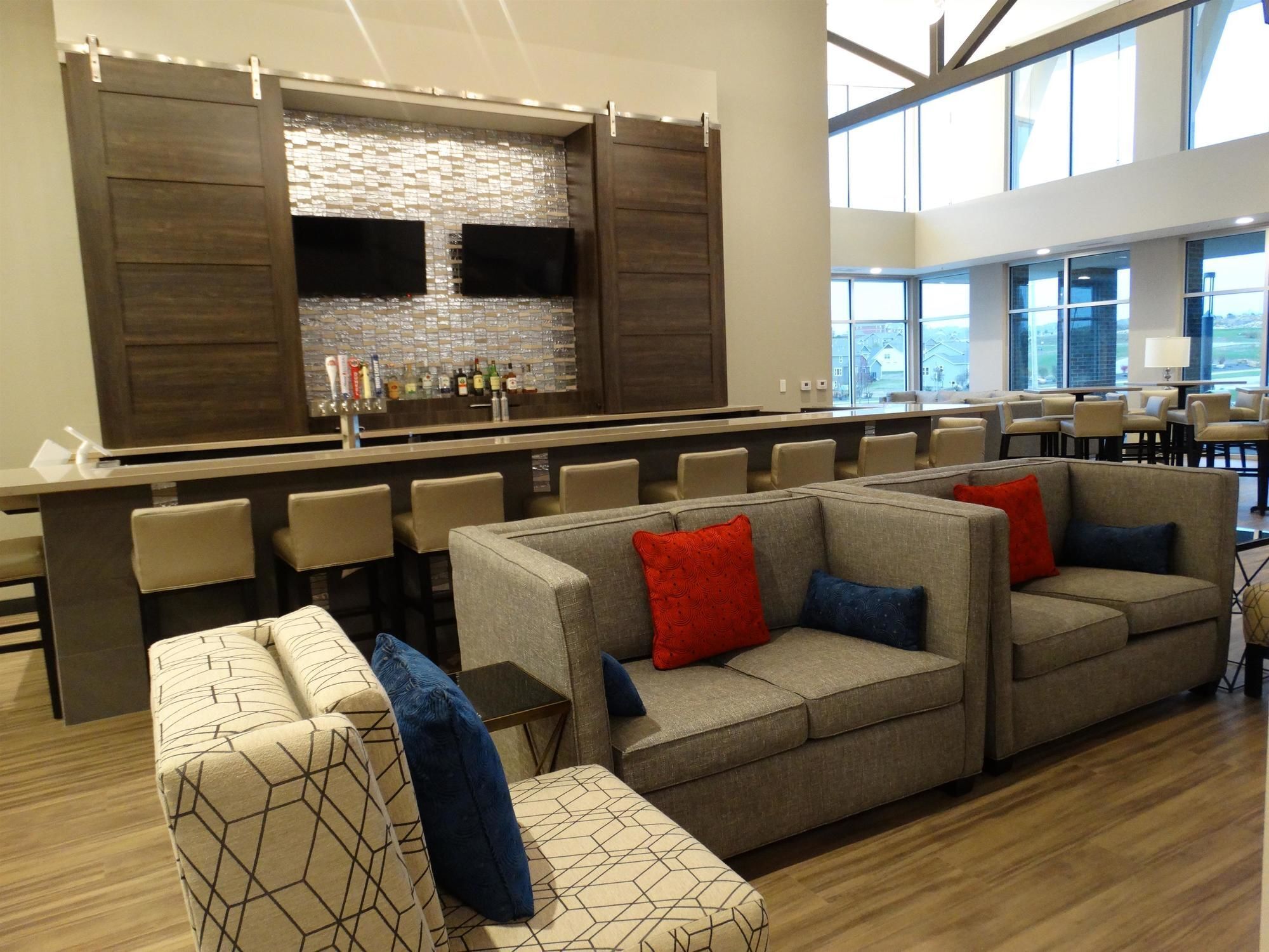 Un espace lounge moderne doté d’un bar, de sièges et de grandes fenêtres.