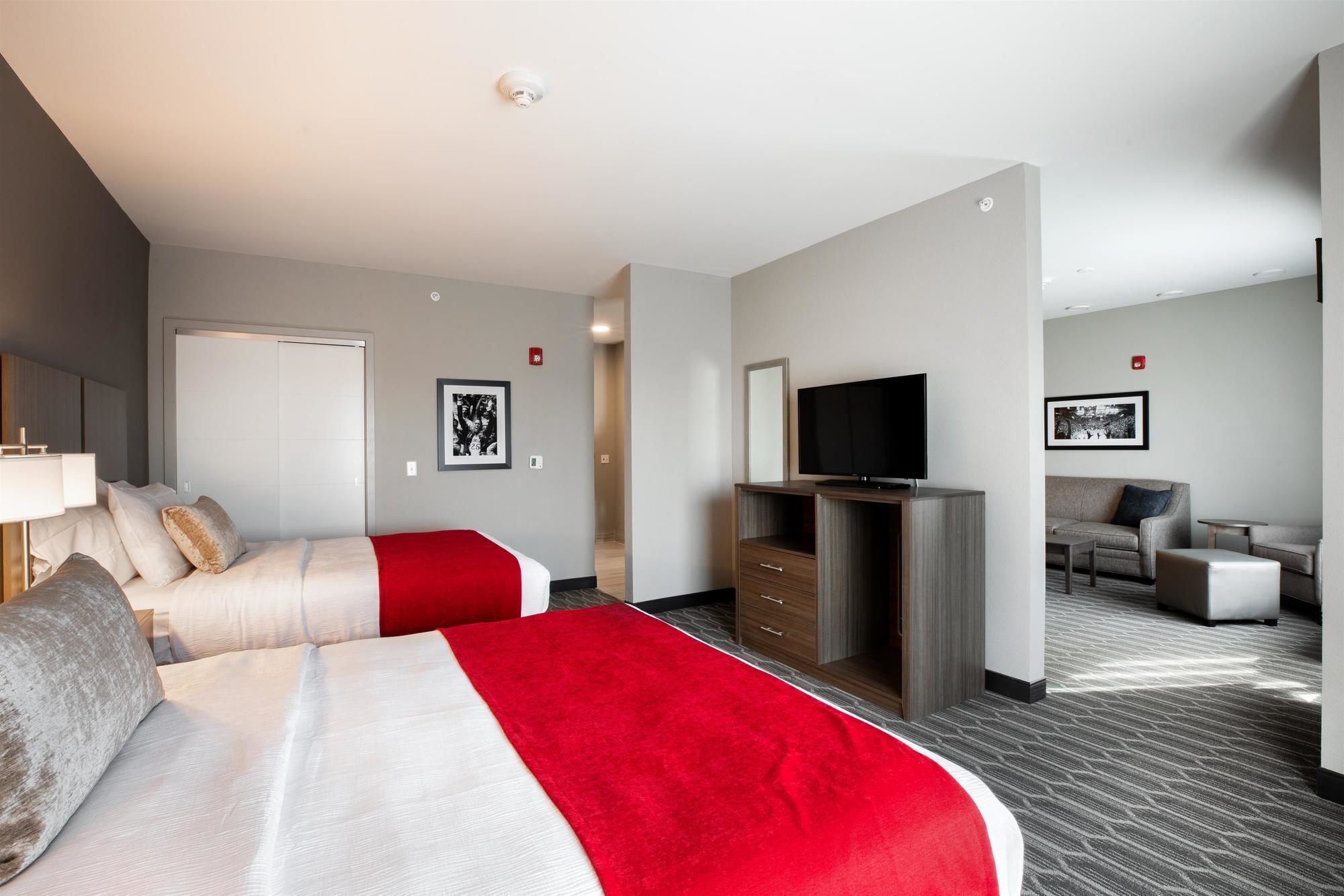 Habitación de hotel con dos camas, un televisor, un sofá y una mesita.