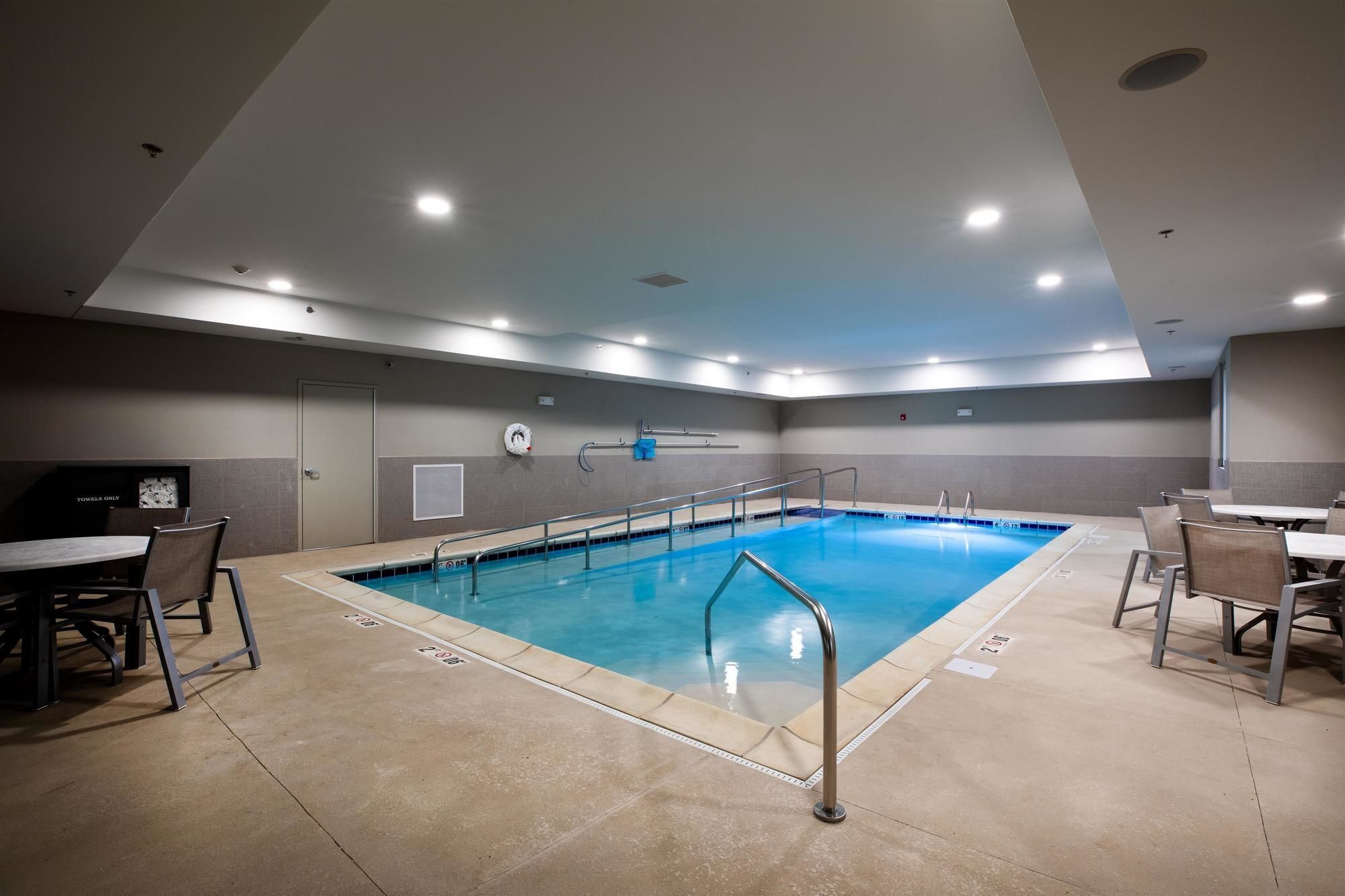 A swimming pool with a tiled deck, a lifeguard chair, and a changing room with a towel rack.
