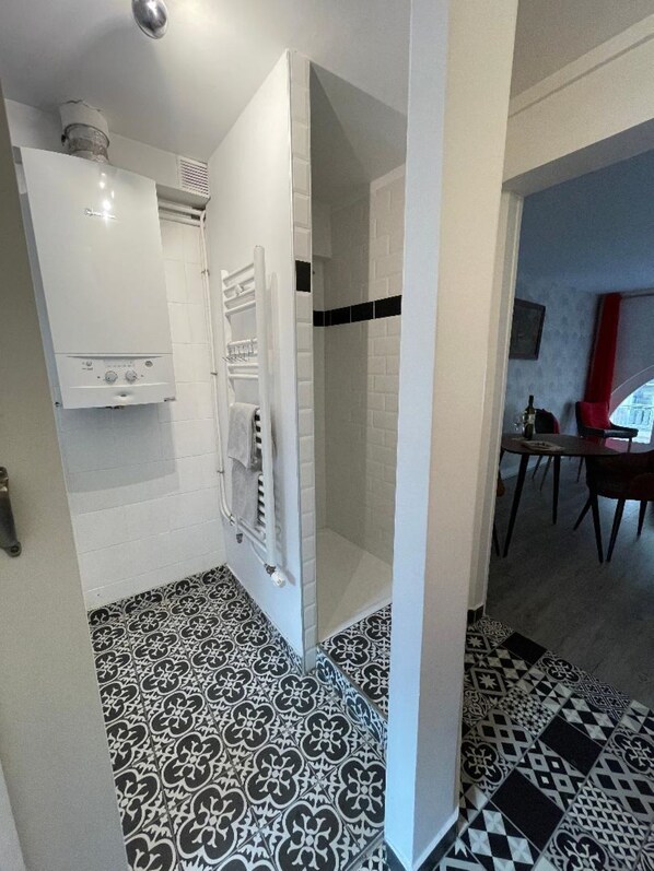 A bathroom with a shower, a toilet, and a sink. There is a patterned floor and a white wall with a vent. - Rivoli/Concorde/Tuilleries (Paris)