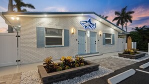 A white brick building with a shark sign, two doors, and a surfboard in the background. - Shark Tank Cocoa Beach • 2 Units • Perfect for Families•Walk to Beach, Bars, & Shops (Cocoa Beach)