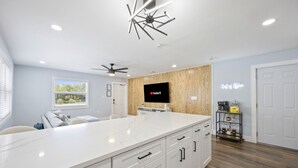 Een moderne keuken met een groot eiland, houten details en een flatscreen televisie.