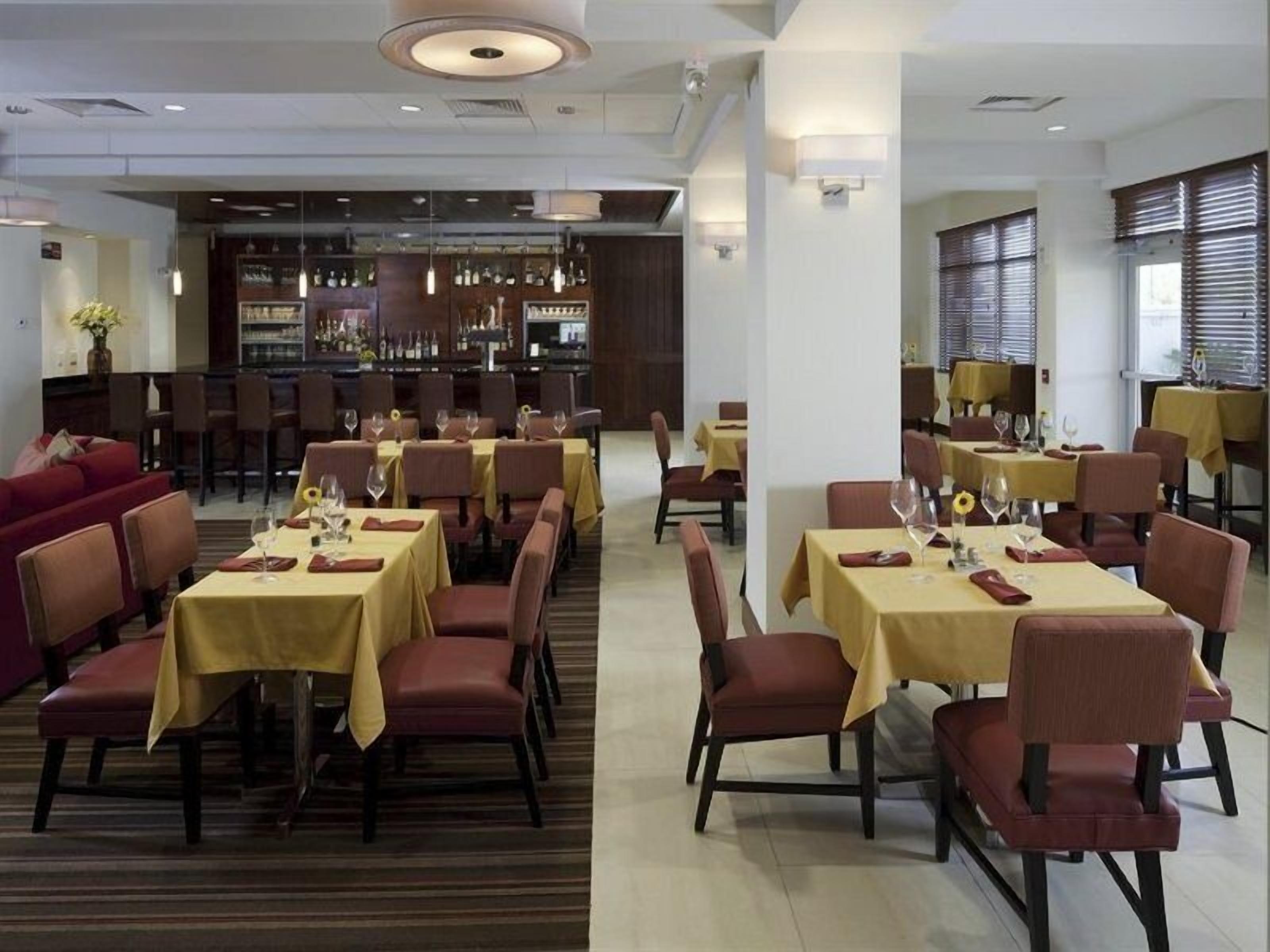 Un restaurante con varias mesas y sillas, una zona de bar y un área de estar con un sofá.