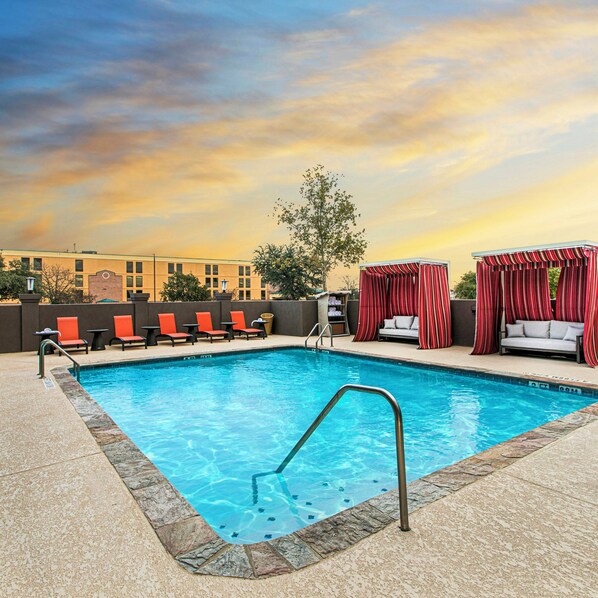 A swimming pool with lounge chairs and a covered seating area.
