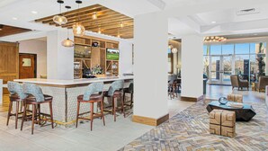 Un espace bar moderne avec un plafond en bois, des tabourets de bar et un téléviseur.