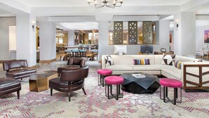 Un vaste espace de vie comprenant un ensemble de canapés, plusieurs fauteuils, une table basse et un lustre.