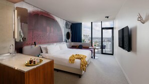 A hotel room with a bed, bedside table, mirror, and a large window with a city view. - Hotel Indigo Sydney Potts Point (Sydney)