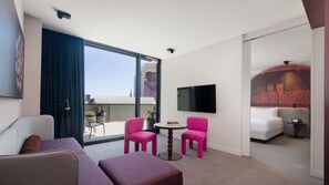 A modern hotel room with a balcony, a TV, a sofa, and a small table. - Hotel Indigo Sydney Potts Point (Sydney)
