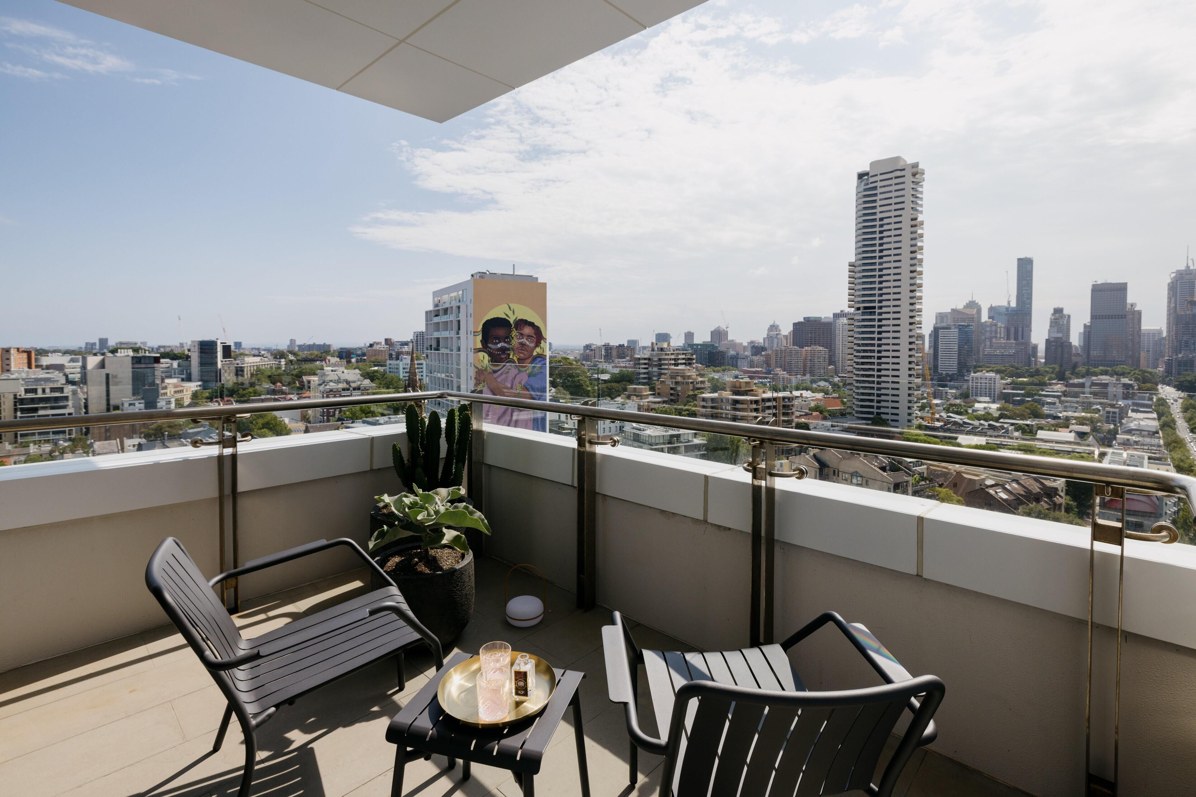 A balcony with two chairs, a table, and a potted plant.