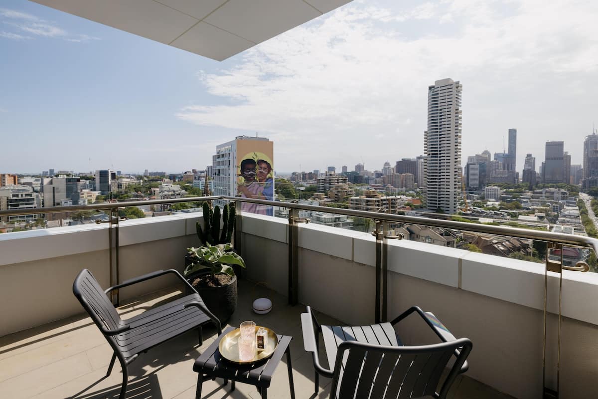 A balcony with two chairs, a table, and a potted plant.