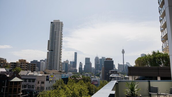 A cityscape with modern high-rise buildings, a prominent tower, and a bus in the foreground.